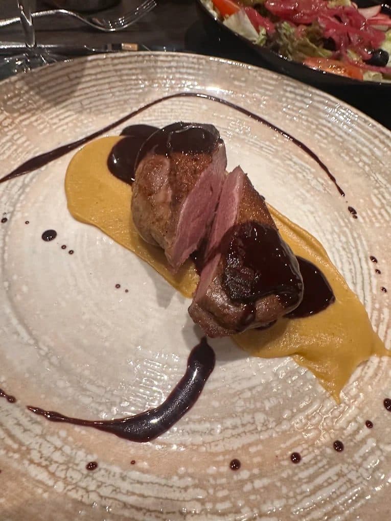Before — Pan-seared duck breast with squash purée — dim restaurant phone photo relit to studio quality with PlateRefresh
