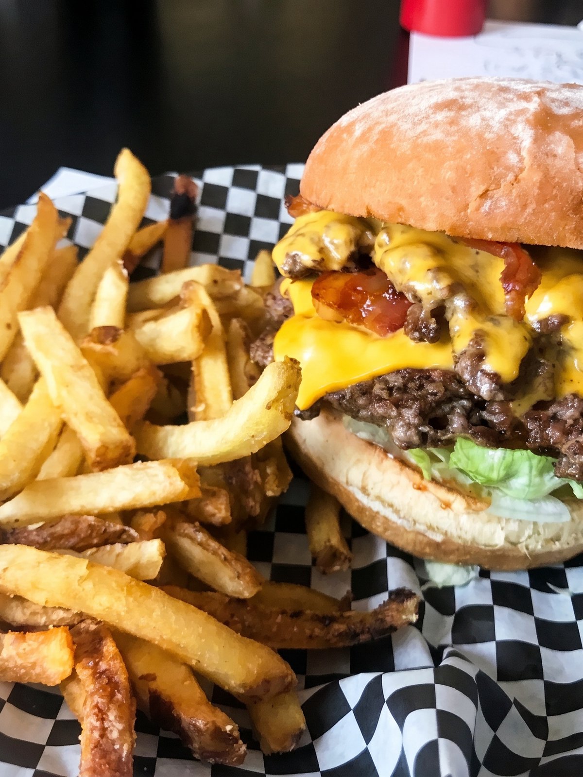 After: brightly lit studio menu photo of the same burger with a glossy bun, melted cheese and crisp sides