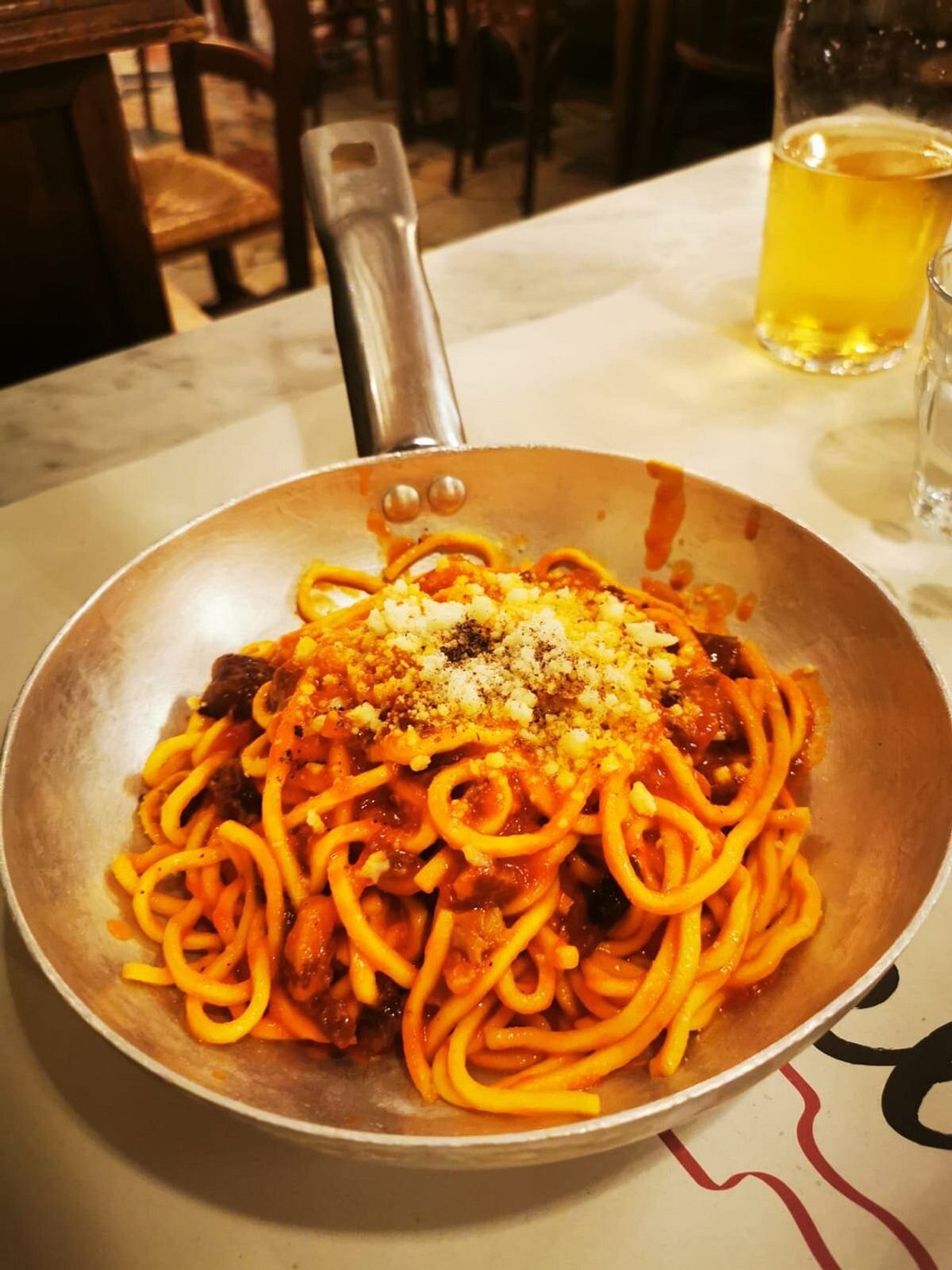 Phone photo of carbonara in a white bowl under harsh overhead light, sauce looking dry and pepper lost in shadow