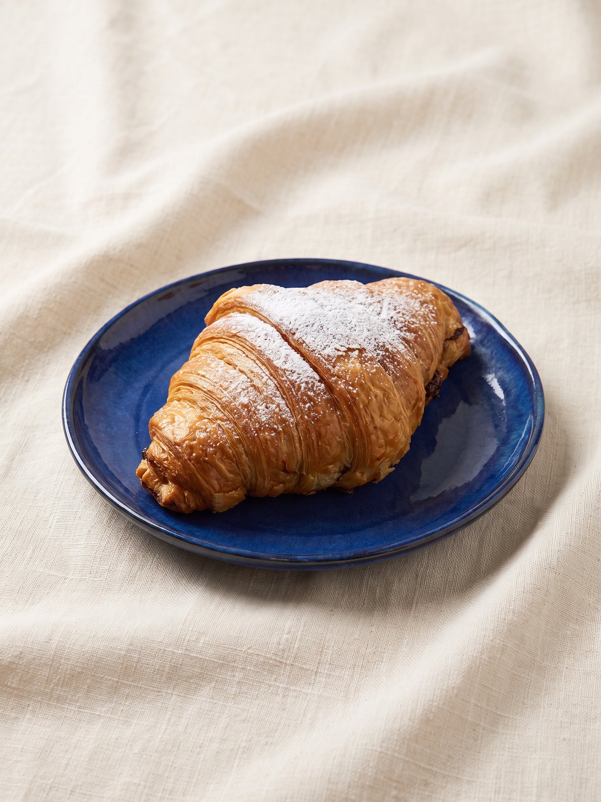 Bakery-grade menu photo of the same croissant with crisp visible layers, golden colour and an appetising glossy sheen