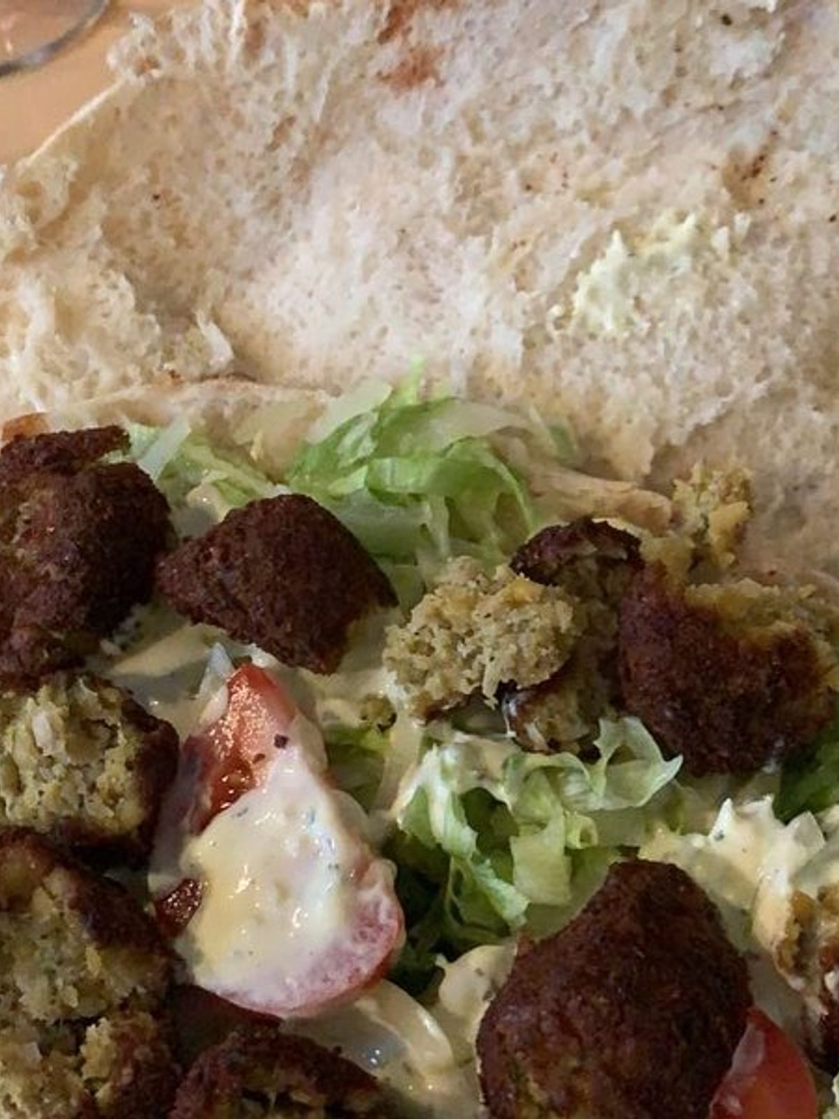 Before: dim phone photo of a falafel plate with sauce and salad on a kitchen counter under flat light