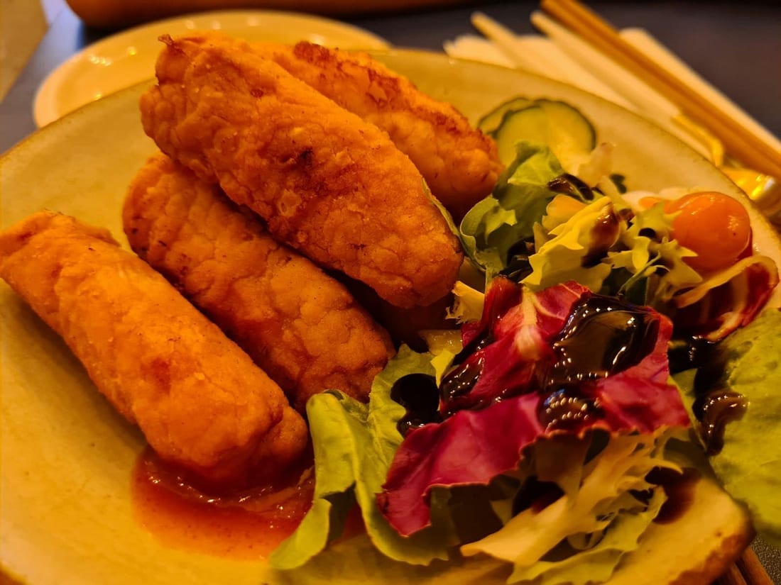 Phone photo of fried chicken under harsh kitchen light with greasy glare flattening the crust texture