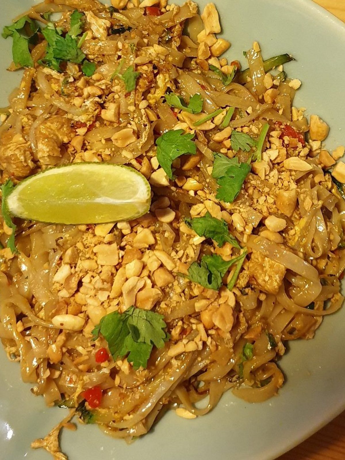 Before: dim phone photo of a plate of pad thai with noodles, peanuts and lime on a kitchen counter