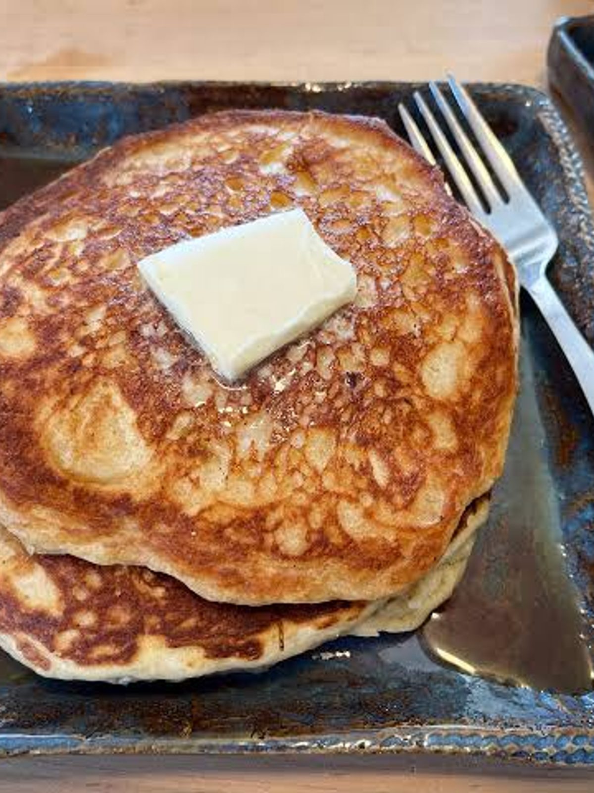 Before: dull phone photo of a stack of pancakes with syrup on a café counter