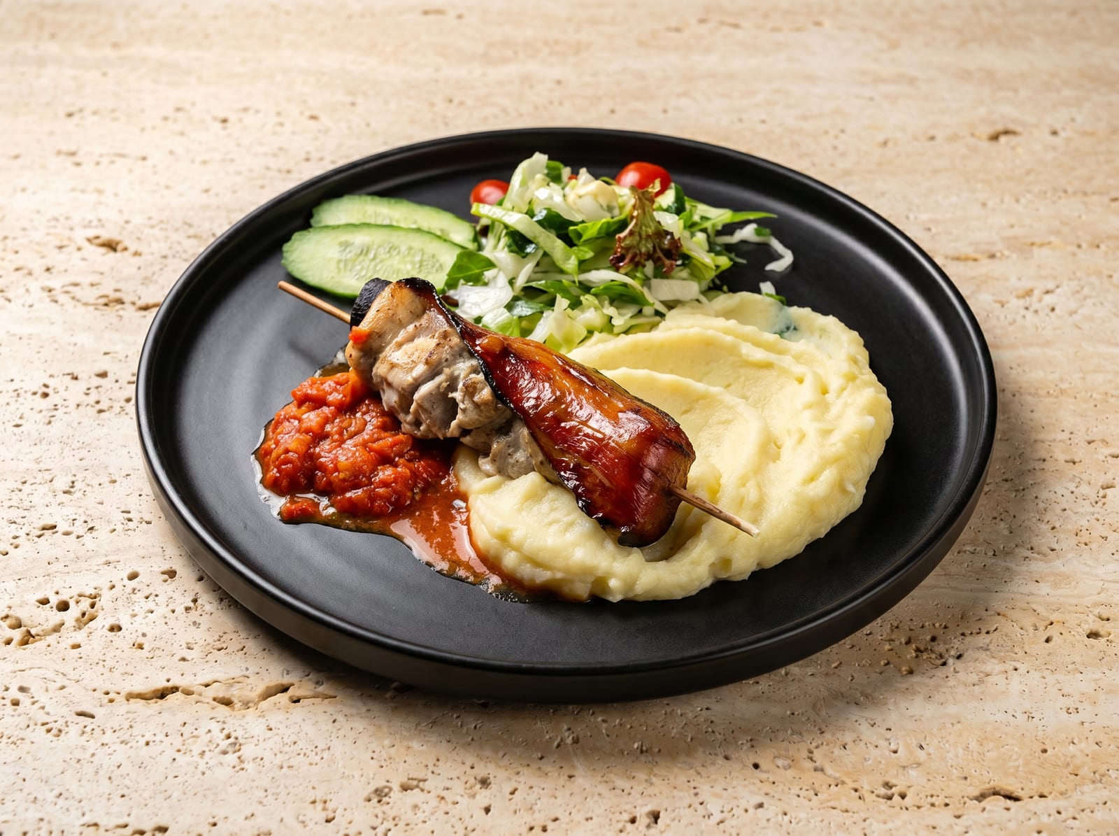 After: warmly lit studio menu photo of the same bacon-wrapped pork skewer with glossy crisped bacon and creamy mash