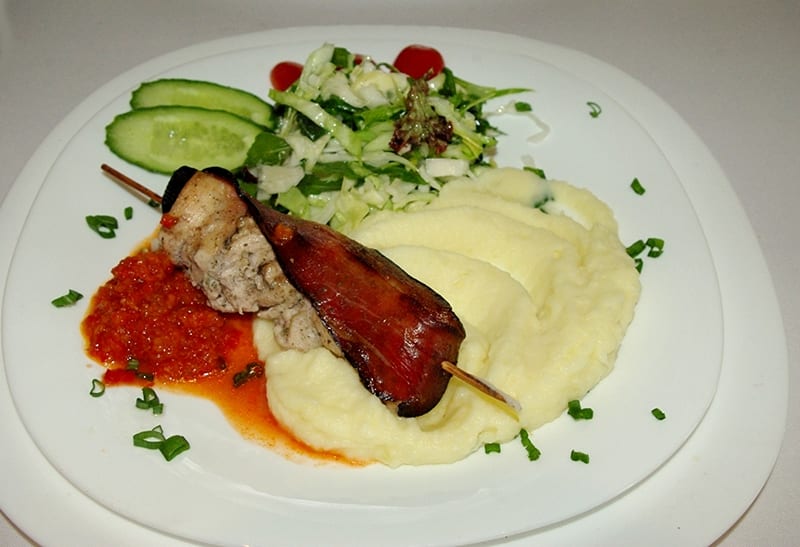 Before: dim phone photo of a bacon-wrapped pork skewer with mashed potatoes on a kitchen counter